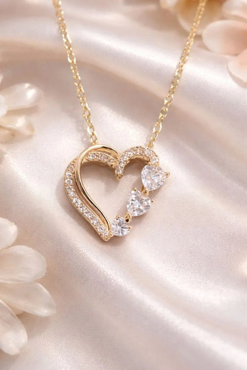 Collier cœur éternel doré avec pierres scintillantes sur satin crème — Maison du Collie