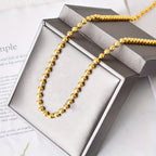 Collier chaîne à perles dorées en acier inoxydable présenté dans son écrin Maison du Collier