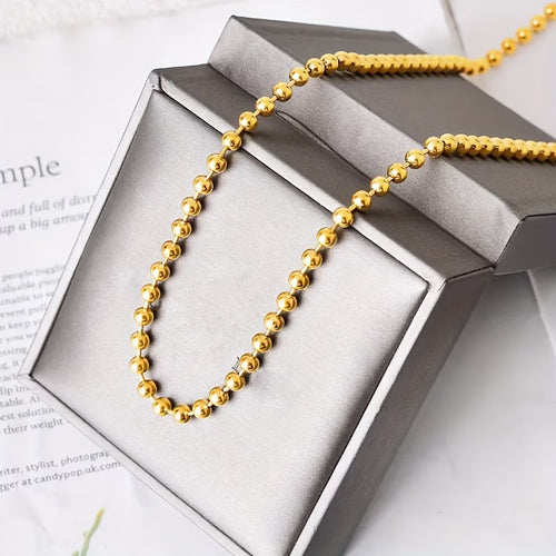 Collier chaîne à perles dorées en acier inoxydable présenté dans son écrin Maison du Collier