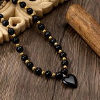 Collier obsidienne noir et doré à pendentif cœur porté par une femme – Maison du Collier