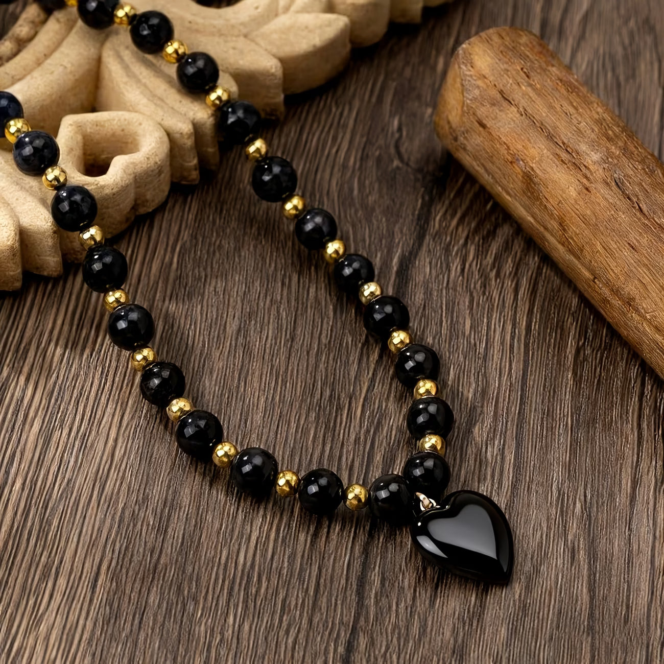Collier obsidienne noir et doré à pendentif cœur porté par une femme – Maison du Collier